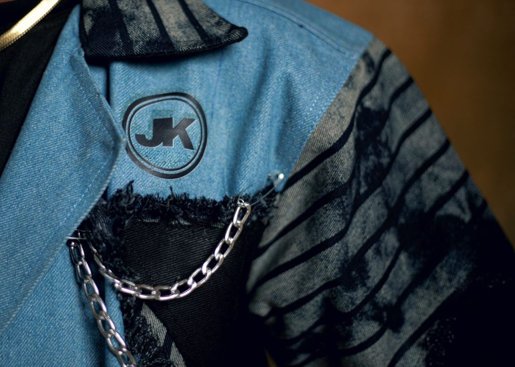 Close-up of a fashionable denim jacket with chain detail, showcasing modern design.