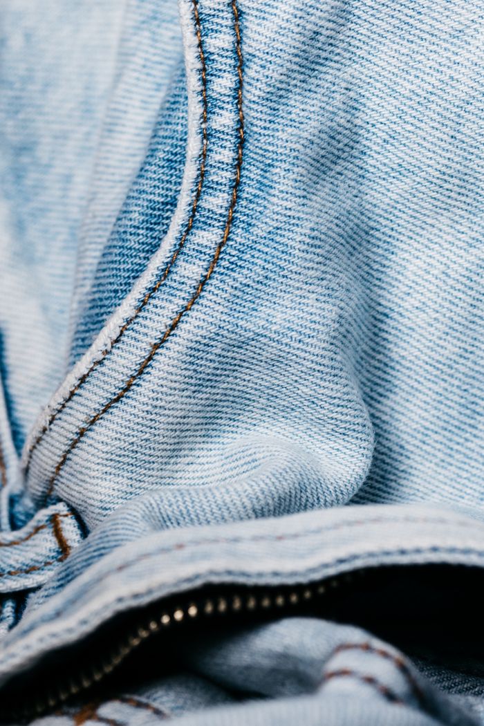 Home Detailed close-up of blue denim fabric showcasing stitching and texture, ideal for fashion and textiles.